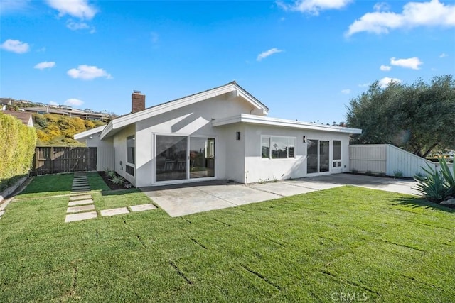 back of property with a yard and a patio