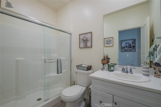 bathroom with a shower with shower door, vanity, and toilet