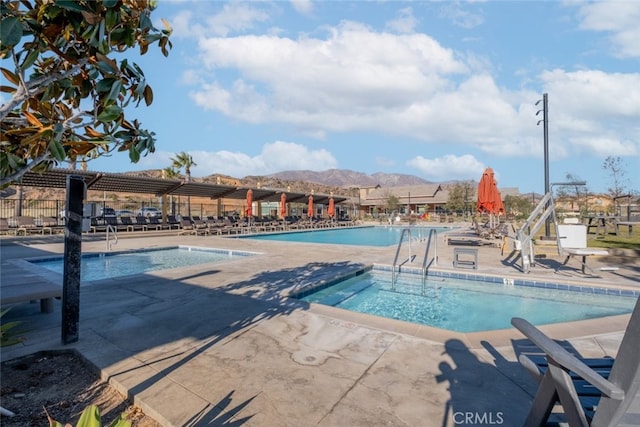 view of pool with a patio area, a mountain view, and a hot tub