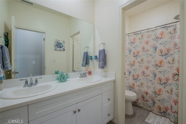 bathroom with tile patterned floors, toilet, vanity, and walk in shower