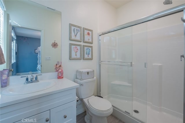 bathroom with toilet, vanity, and an enclosed shower