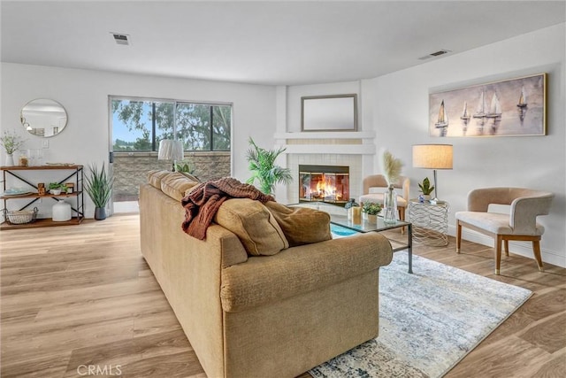 living room featuring a tile fireplace and light hardwood / wood-style flooring