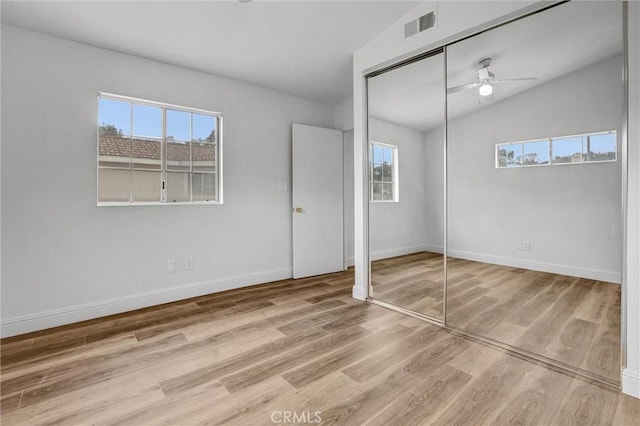 unfurnished bedroom with light hardwood / wood-style floors, multiple windows, a closet, and lofted ceiling