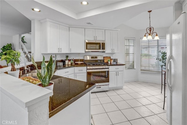 kitchen with kitchen peninsula, appliances with stainless steel finishes, white cabinetry, and a notable chandelier