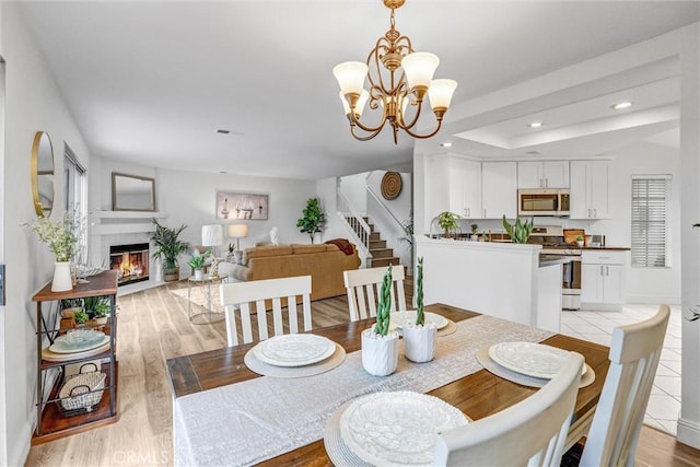 dining space featuring light wood-type flooring and an inviting chandelier