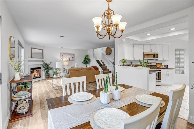 16096 Caminito Tomas, San Diego, CA 92128 - dining room featuring recessed lighting, stairs, a glass covered fireplace, a chandelier, and light wood-style flooring