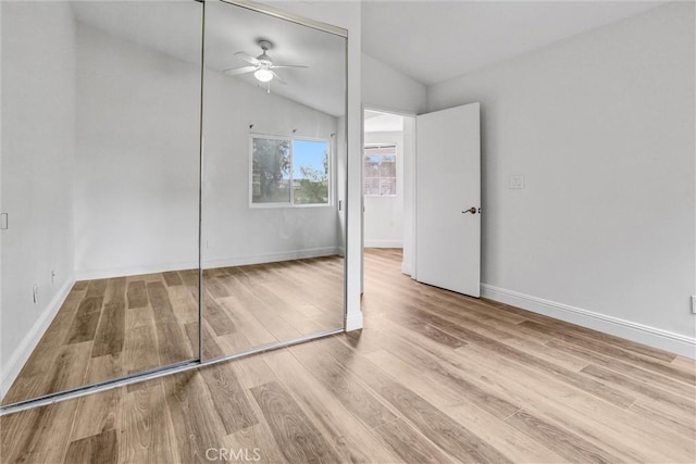 unfurnished bedroom featuring lofted ceiling, a closet, and hardwood / wood-style floors