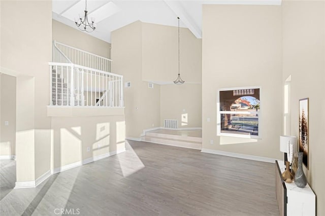 living room featuring hardwood / wood-style flooring, an inviting chandelier, a high ceiling, and beamed ceiling