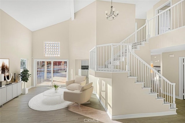 living room featuring a towering ceiling, wood-type flooring, and a notable chandelier