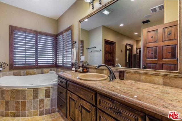 bathroom with a relaxing tiled tub and vanity