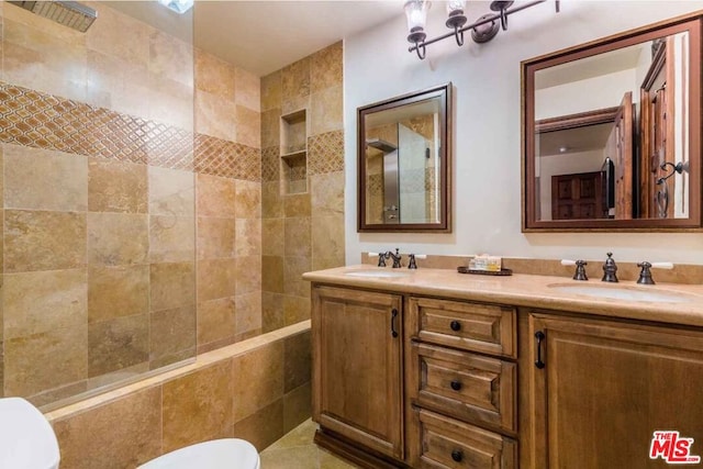 bathroom featuring toilet, vanity, and tiled shower