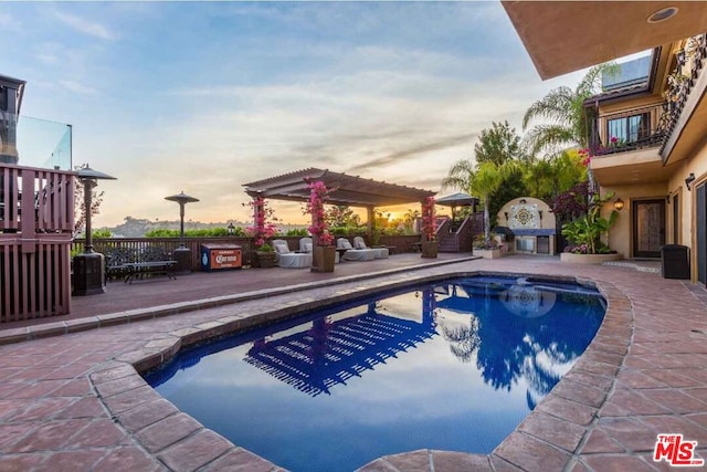 pool at dusk featuring a pergola and a patio area