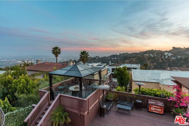 deck at dusk featuring a gazebo