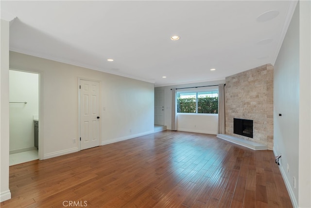 unfurnished living room featuring ornamental molding, hardwood / wood-style floors, and a stone fireplace