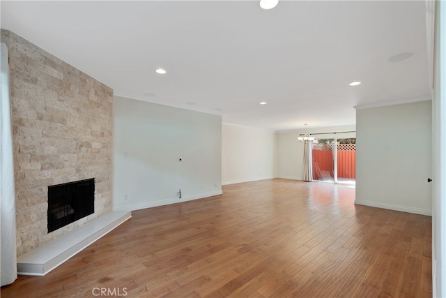 unfurnished living room featuring light hardwood / wood-style floors, ornamental molding, a notable chandelier, and a fireplace