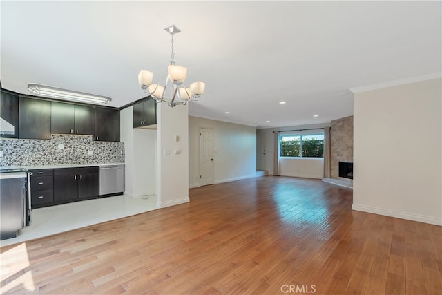 kitchen featuring a fireplace, dishwasher, decorative backsplash, light wood-type flooring, and a chandelier