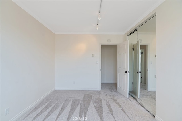 spare room with light carpet, crown molding, and rail lighting