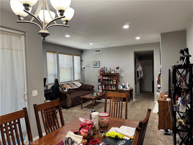 carpeted dining area with a chandelier