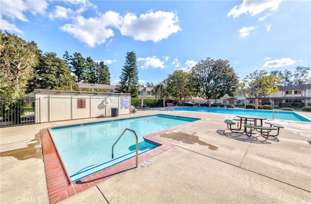 pool with a patio area and fence