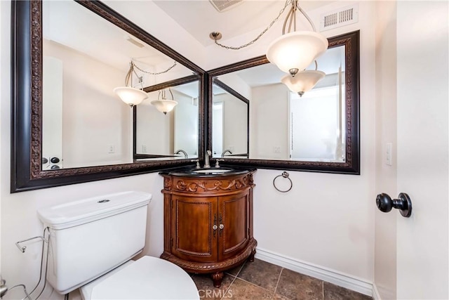 half bath with toilet, vanity, visible vents, and baseboards