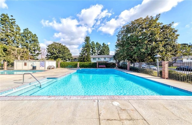 community pool with a patio area and fence