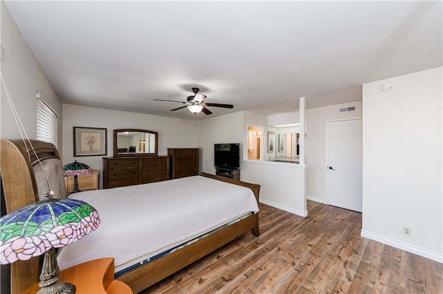 bedroom with baseboards, visible vents, ceiling fan, and wood finished floors