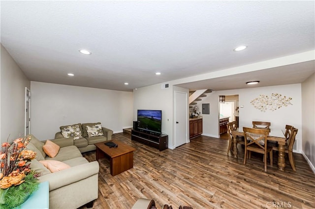 living room featuring recessed lighting, wood finished floors, a textured ceiling, and stairs