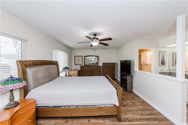 bedroom featuring a ceiling fan, connected bathroom, baseboards, and wood finished floors