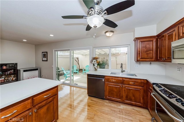 kitchen featuring appliances with stainless steel finishes, light countertops, a sink, and light wood finished floors