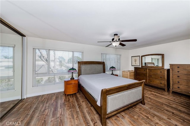 bedroom with multiple windows, wood finished floors, a ceiling fan, and baseboards