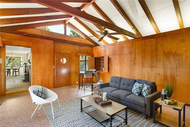 living room with ceiling fan, carpet, beamed ceiling, wooden walls, and high vaulted ceiling