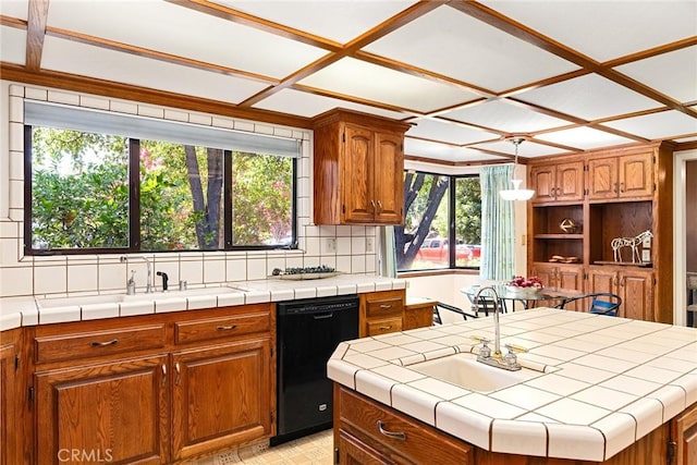 kitchen with tile counters, dishwasher, a kitchen island with sink, and tasteful backsplash