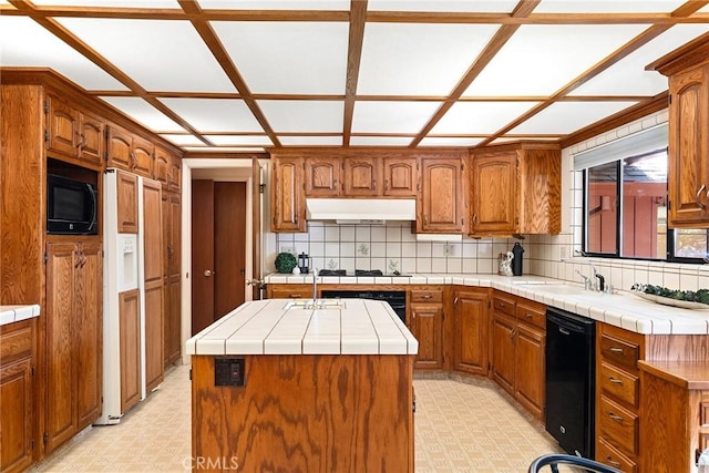 kitchen featuring black appliances, sink, backsplash, a kitchen island with sink, and tile countertops