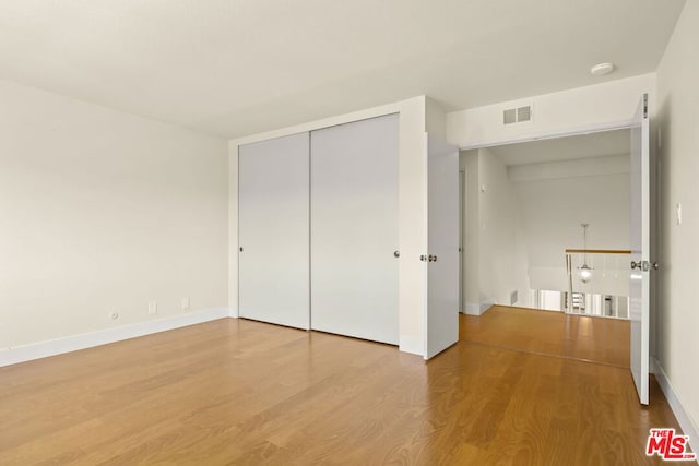 unfurnished bedroom featuring wood-type flooring and a closet