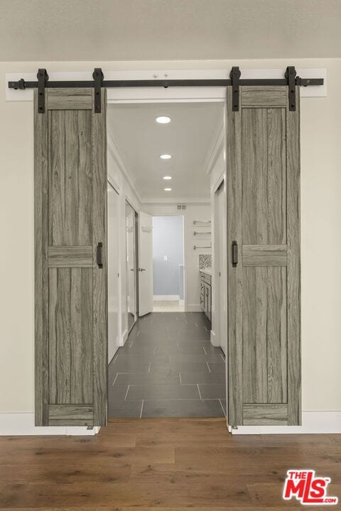 corridor with a barn door and dark wood-type flooring