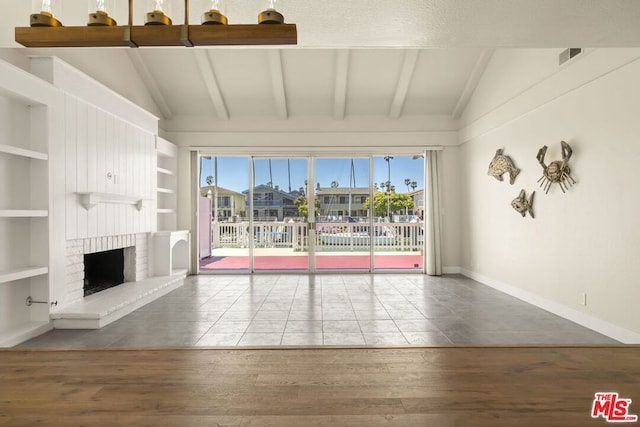 unfurnished living room featuring wood-type flooring, built in shelves, and a healthy amount of sunlight