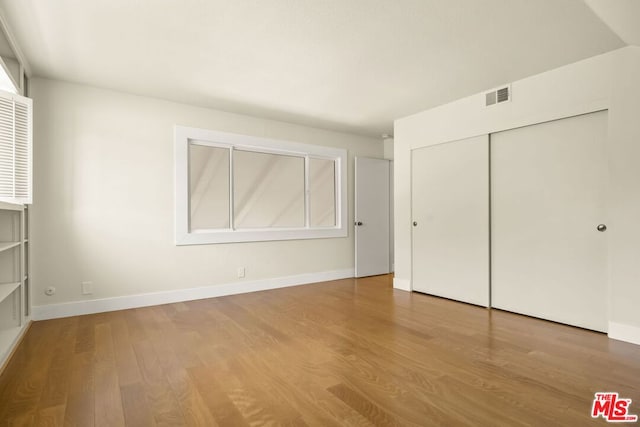 unfurnished bedroom featuring hardwood / wood-style floors and a closet