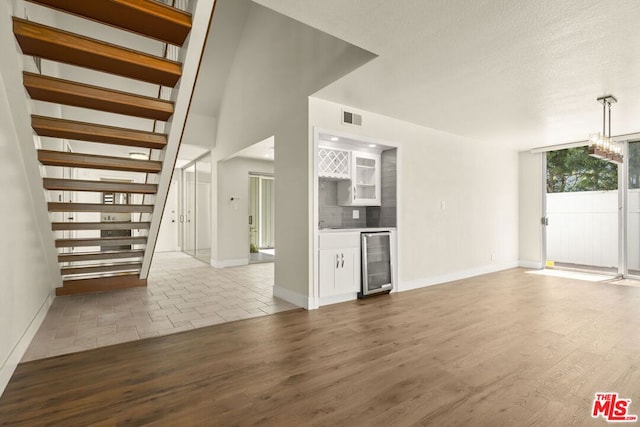 unfurnished living room featuring wine cooler and hardwood / wood-style flooring