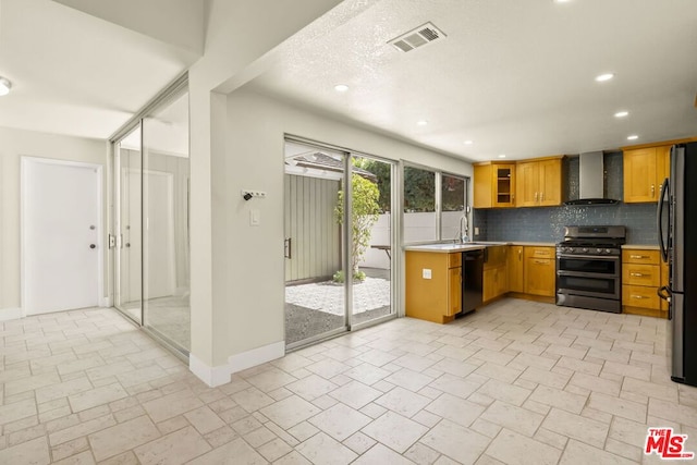 kitchen featuring stainless steel appliances, wall chimney exhaust hood, backsplash, and sink