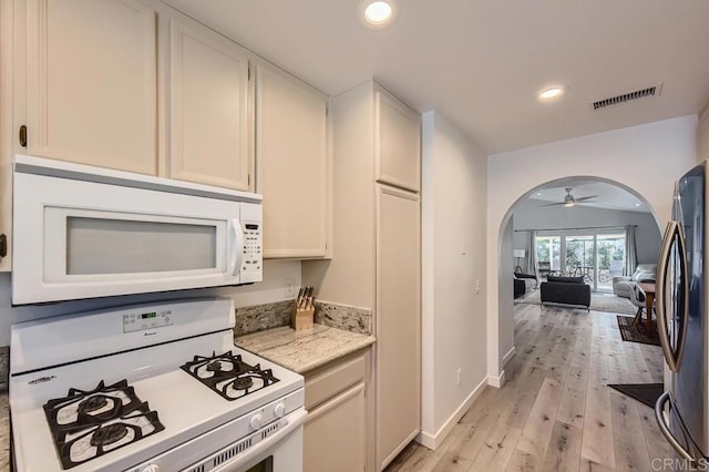 kitchen with ceiling fan, white appliances, white cabinetry, light hardwood / wood-style flooring, and light stone counters