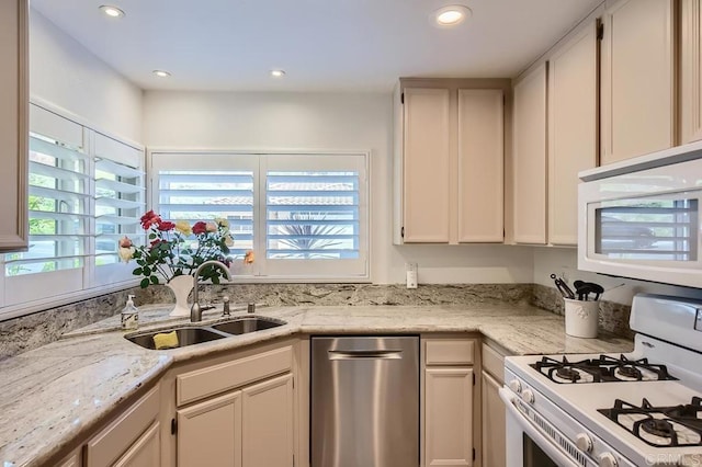 kitchen with light stone countertops, sink, white cabinets, and white appliances