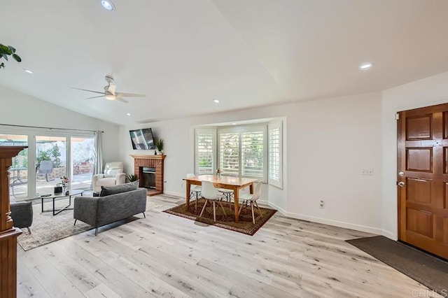 living room with ceiling fan, vaulted ceiling, light hardwood / wood-style flooring, and a fireplace