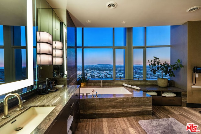 bathroom with vanity, a wall of windows, hardwood / wood-style flooring, and a tub