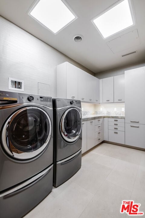 clothes washing area featuring washing machine and dryer and cabinets