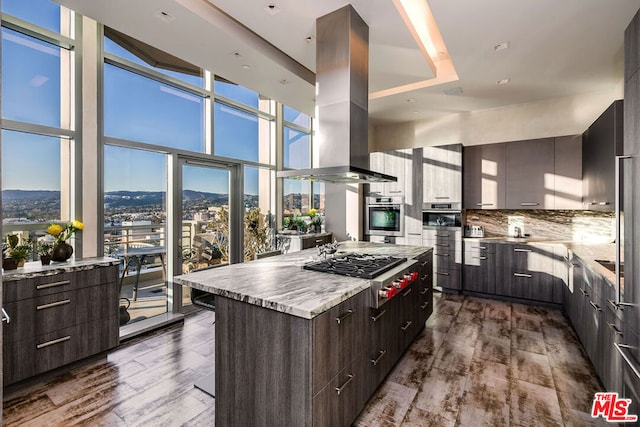 kitchen with island range hood, stainless steel appliances, plenty of natural light, dark hardwood / wood-style flooring, and a center island