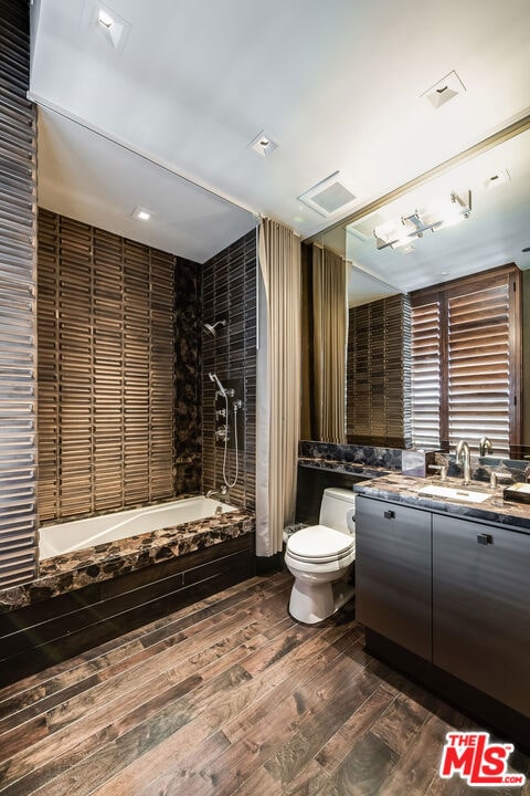 full bathroom with toilet, tiled shower / bath, wood-type flooring, and vanity