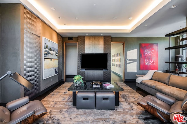 living room with dark hardwood / wood-style flooring and a raised ceiling