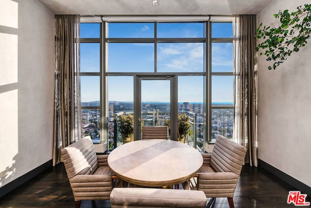 dining area featuring dark wood-type flooring, a wall of windows, and a towering ceiling