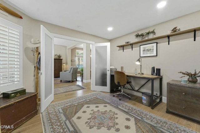 office with light wood-type flooring and french doors