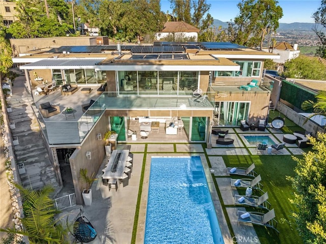 rear view of property featuring a pool with hot tub, solar panels, a patio area, and a mountain view